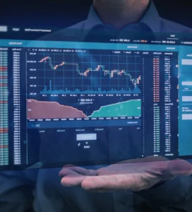 A man is holding a computer screen with a stock chart on it